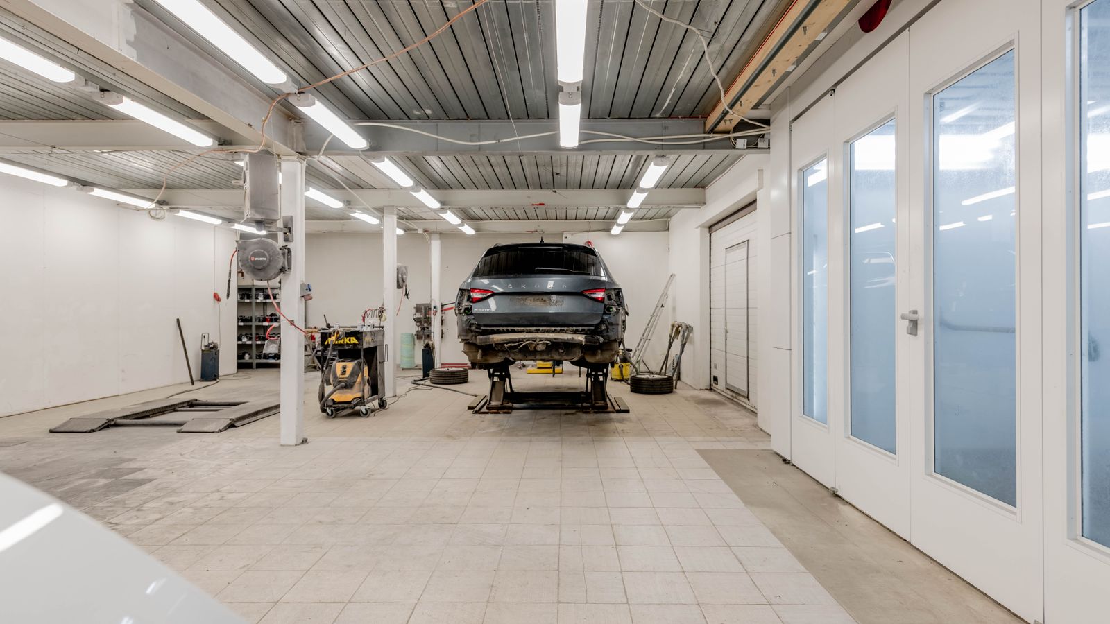Taller moderno con un coche en el elevador y el resto de la nave vacía