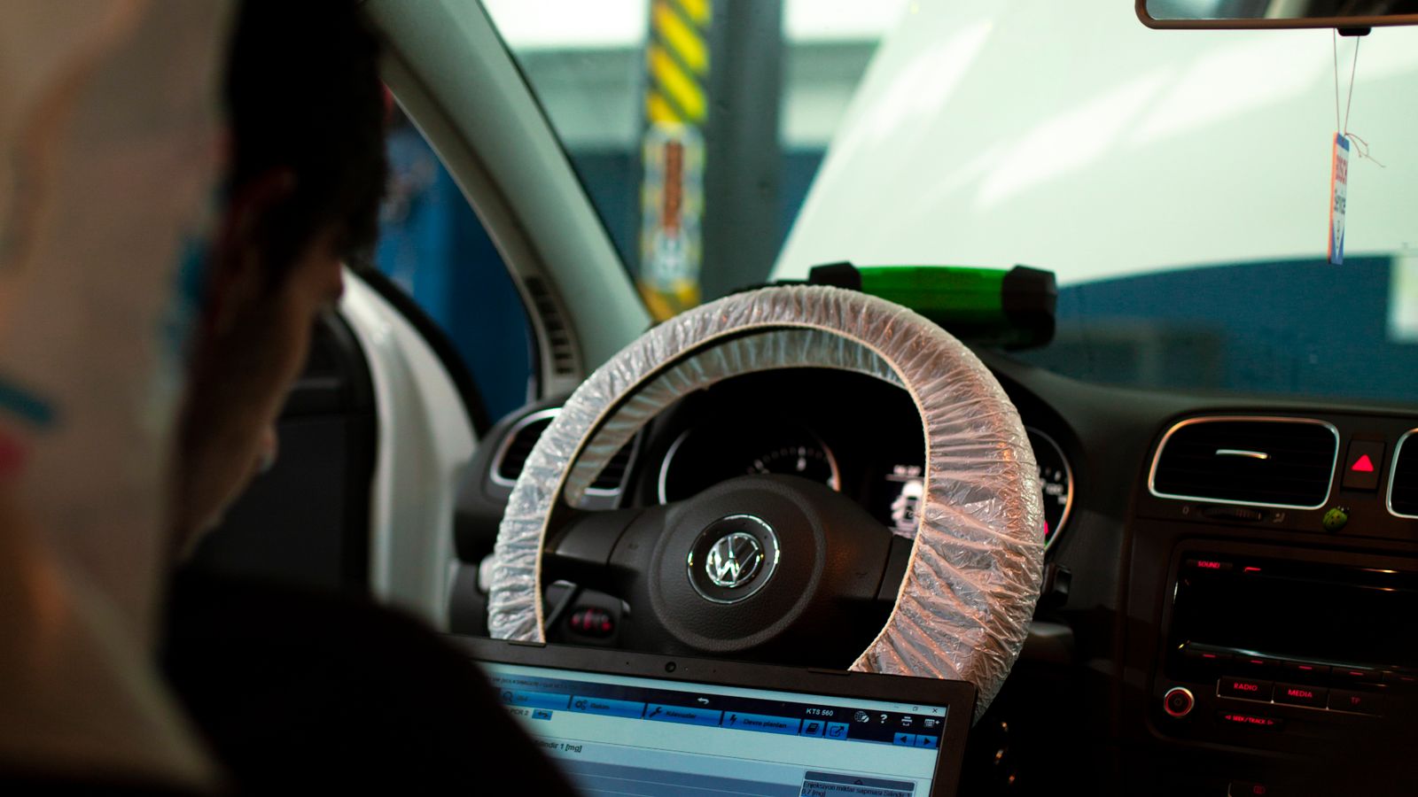 Mecánico usando un portátil sentado en el asiento del conductor durante una diagnosis